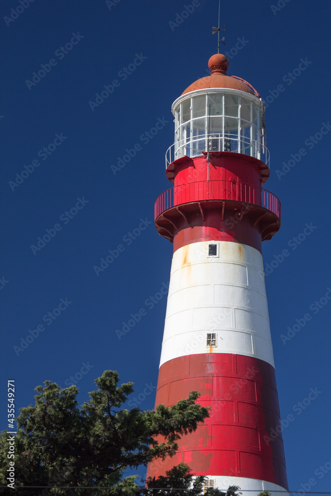 Close-up of coastal lighthouse. White and red lighthouse that contrasts with the beautiful, totally clear blue sky. Summer concept, sign, guide. Faro Punta Mogotes, Mar del Plata. Argentina.