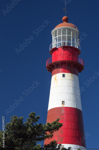 Close-up of coastal lighthouse. White and red lighthouse that contrasts with the beautiful, totally clear blue sky. Summer concept, sign, guide. Faro Punta Mogotes, Mar del Plata. Argentina.