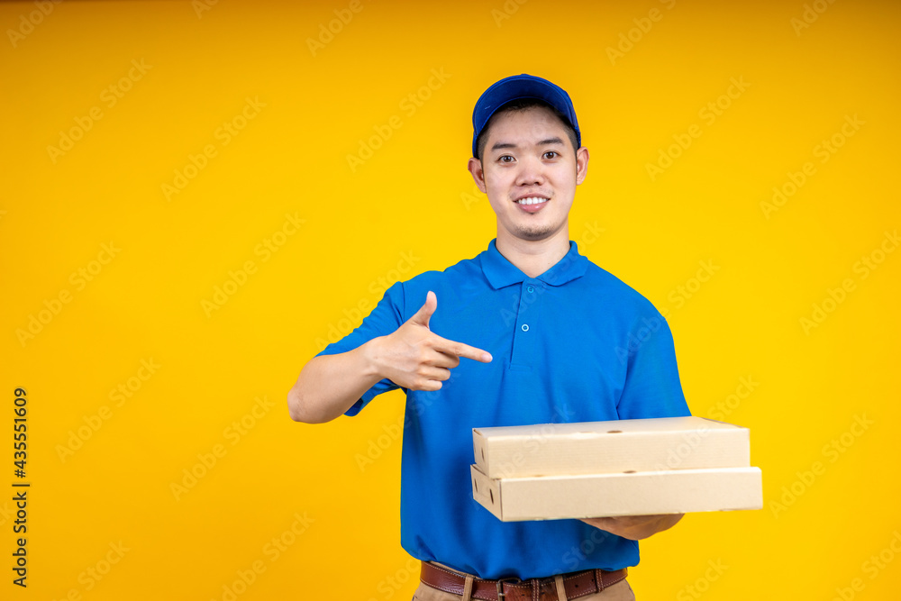Young Asian handsome delivery man pointing to pizza boxs over yellow isolate background. Work from home and delivery concept. Young Asian handsome delivery man pointing to pizza boxs over yellow isolate background. Work from home and delivery concept.