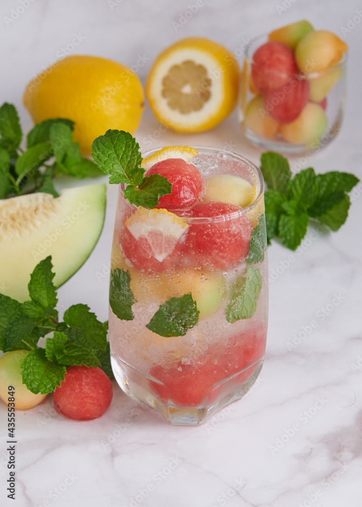Refreshing summer citrus cocktail with lemon, watermelon and melon with mint and ice cubes in glass, homemade fresh fruit, fruit drink for healthy concept, selective focus. Refreshing summer citrus cocktail with lemon, watermelon and melon with mint and ice cubes in glass, homemade fresh fruit, fruit drink for healthy concept, selective focus.