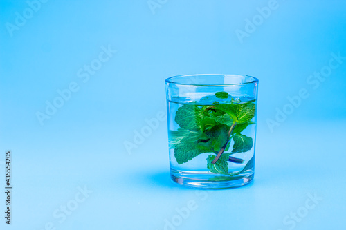 Fresh water in glass with mint on aqua blue background. Part of set.