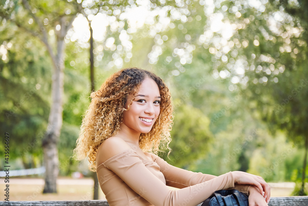 Woman with afro hair, in the forest having fun happy. Latina girl sitting on park bench. Woman with afro hair, in the forest having fun happy. Latina girl sitting on park bench.
