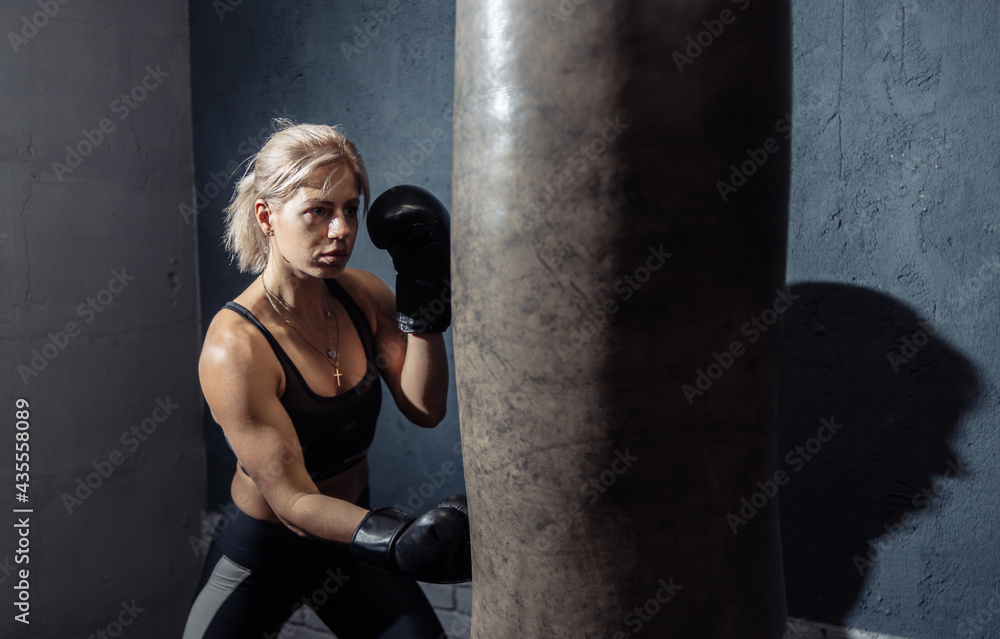 Woman boxing trains punching with a punching bag. Lifestyle