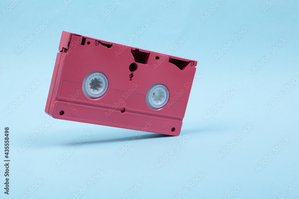 Obraz premium Levitating pink video cassette on blue background. 3D photo. Minimalistic still life. Creative layout. Concept art