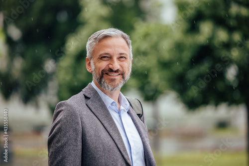 Positive man, standing outdoor, in the park.