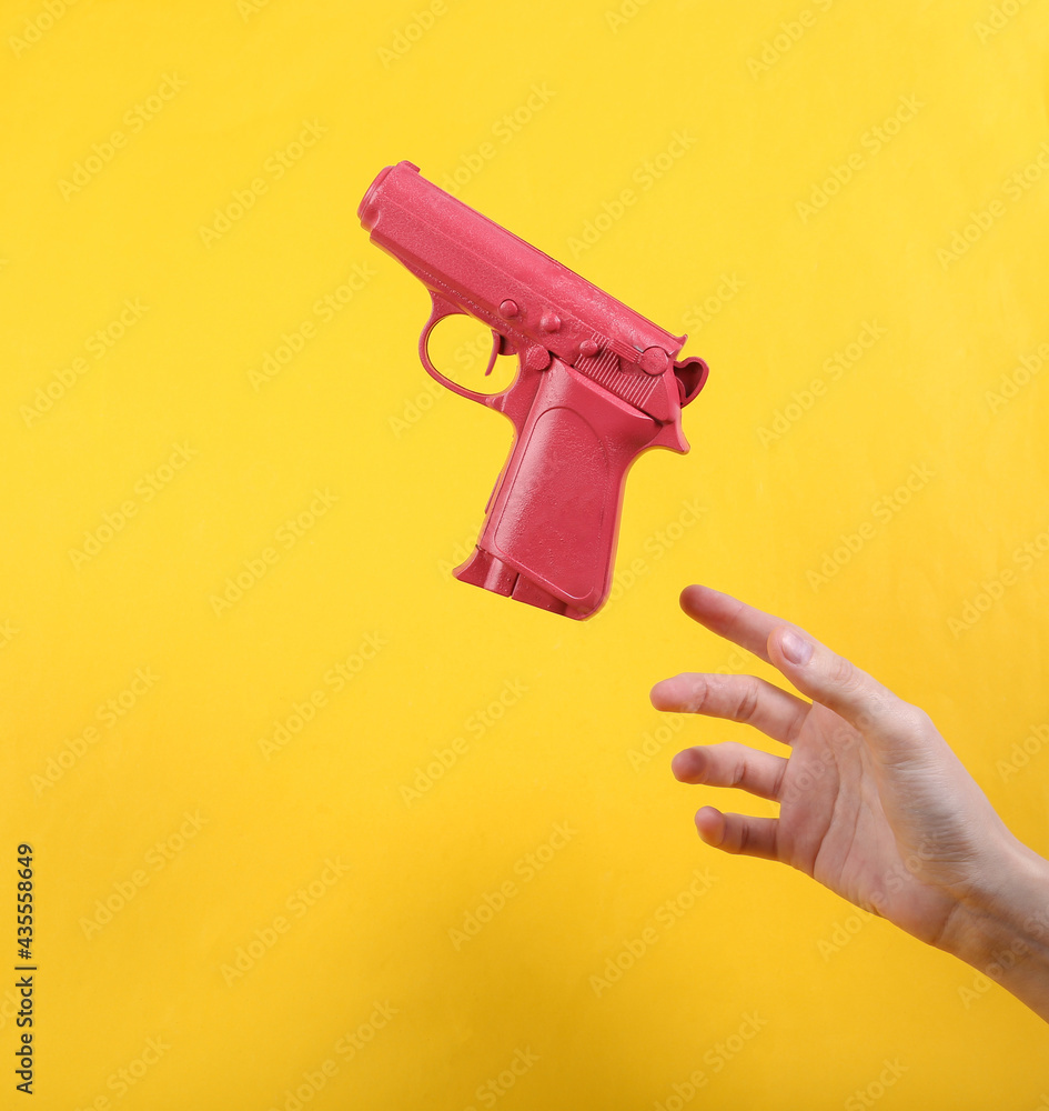 Hand and Levitating pink gun on yellow background. Minimalistic still life. Concept art. Video game Hand and Levitating pink gun on yellow background. Minimalistic still life. Concept art. Video game
