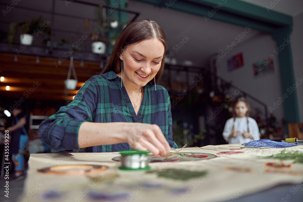 Fototapeta premium Flourist shop with different kinds of dryed flowers. Young happy confident specialist is working with her female kid.