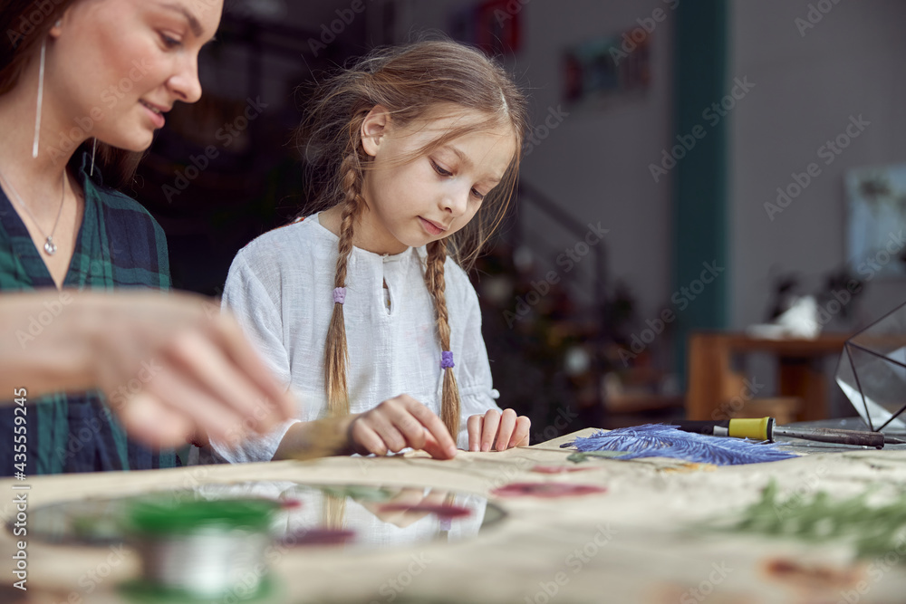 Fototapeta premium Flourist shop with different kinds of dryed flowers. Young happy confident specialist is working with her female kid.