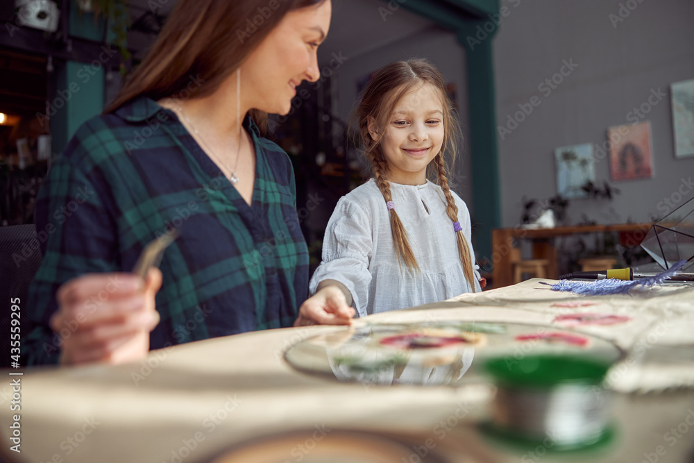 Fototapeta premium Flourist shop with different kinds of dryed flowers. Young happy confident specialist is working with her female kid.