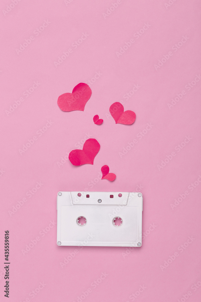 White painted audio cassette and hearts on pink background. Minimalism. Top view White painted audio cassette and hearts on pink background. Minimalism. Top view