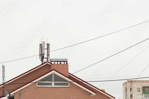 Telecommunication antenna next to the chimney on the roof of the house. Cellular and telephone communications. Chimney against the gray sky. The concept of modern life in the city.