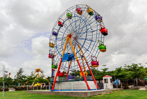 A multicolor Ferris wheel in a public water park. Side view. Telangana Hyderabad Tourism.