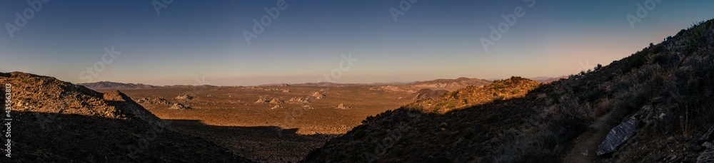Panorama shot of dry desert land with dusty path and shadow in joshua tree national park in america