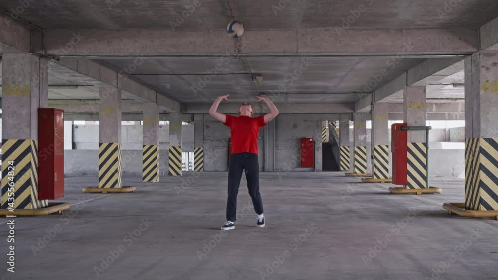 Young girl in red t shirt and black trousers practices bump hits with volleyball ball. Amatuer trains by herself. Young girl in red t shirt and black trousers practices bump hits with volleyball ball. Amatuer trains by herself.