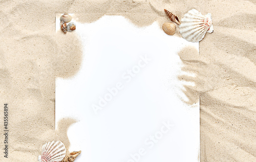 a white sheet of paper in the sand with shells