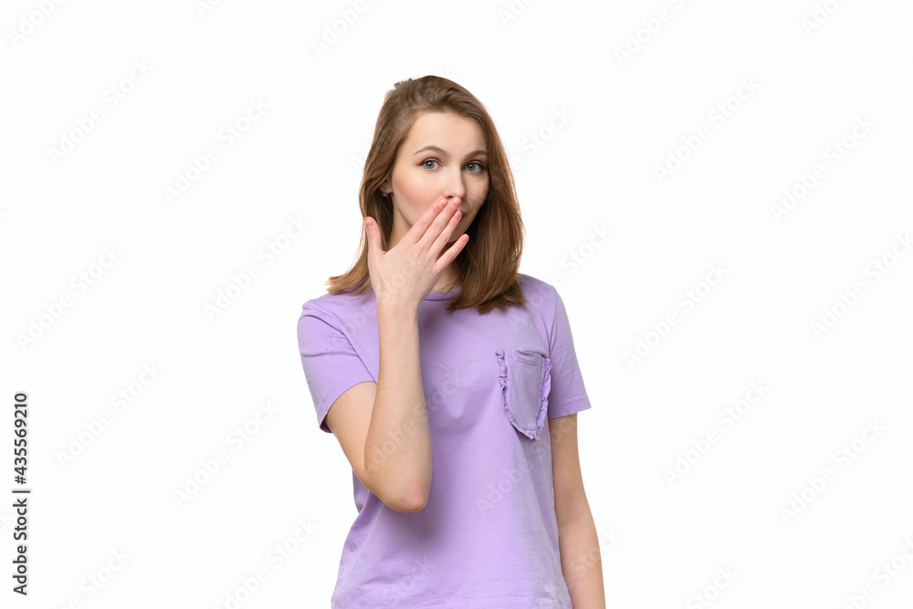 Young woman covering mouth with hand, looking serious, promises to keep secret. . Studio shot, white background Young woman covering mouth with hand, looking serious, promises to keep secret. . Studio shot, white background