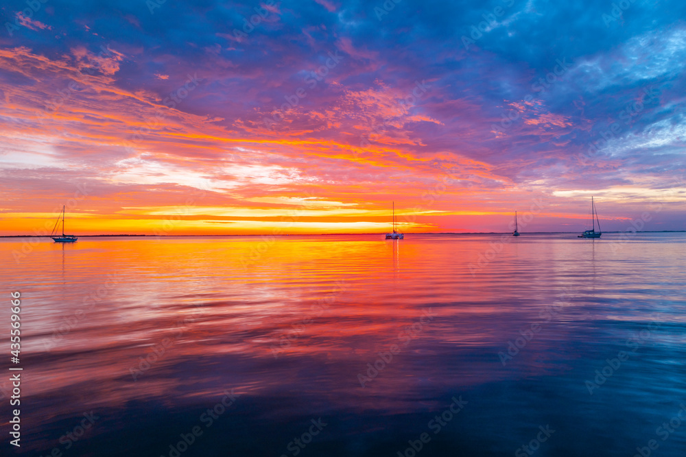 Calm sea with sunset sky and sun through the clouds over. Ocean and sky background, seascape.