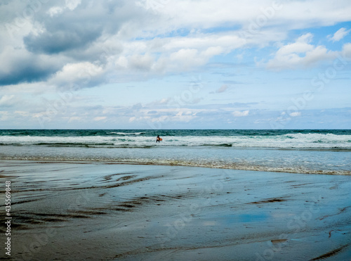 Closeup shot of surfer entering the sea at Sopelana beach in Spain on a cloudy day