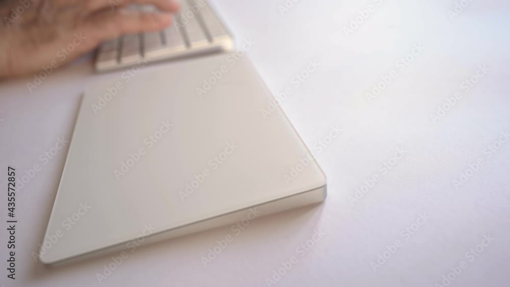 Close-up of man's hands typing on wireless white keyboard and touchpad surfing and chatting on internet. New human habits for social contacts due to technology and social network media diffusion Close-up of man's hands typing on wireless white keyboard and touchpad surfing and chatting on internet. New human habits for social contacts due to technology and social network media diffusion