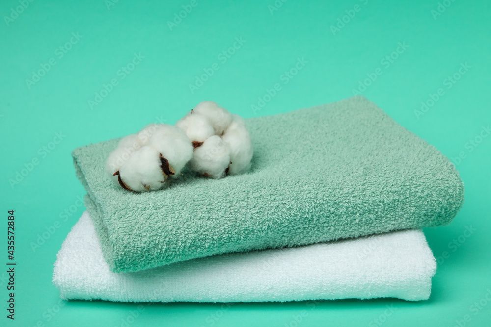 Clean folded towels and cotton on mint background Clean folded towels and cotton on mint background