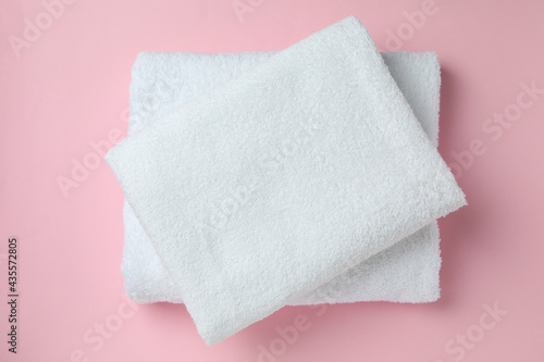 Clean folded towels on pink background, top view