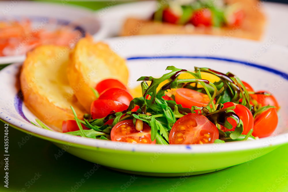 Baked camambert cheese with jam and fresh vegetable salad made from cherry tomatoes and green arugula Baked camambert cheese with jam and fresh vegetable salad made from cherry tomatoes and green arugula