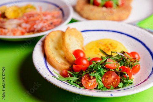 Baked camambert cheese with jam and fresh vegetable salad made from cherry tomatoes and green arugula