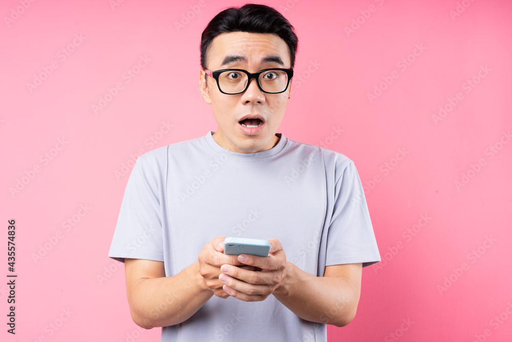 Portrait of Asian man using smartphone on pink background Portrait of Asian man using smartphone on pink background