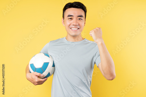 Asian man holding ball with victory expression