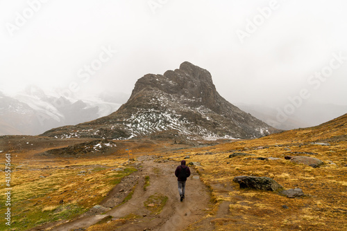 Mann mit Jacke und Kapuze wandert durch Berglandschaft in den Alpen der Schweiz