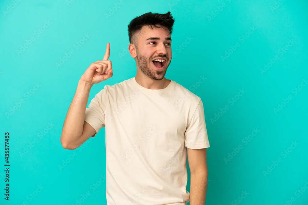 Young caucasian man isolated on blue background intending to realizes the solution while lifting a finger up Young caucasian man isolated on blue background intending to realizes the solution while lifting a finger up