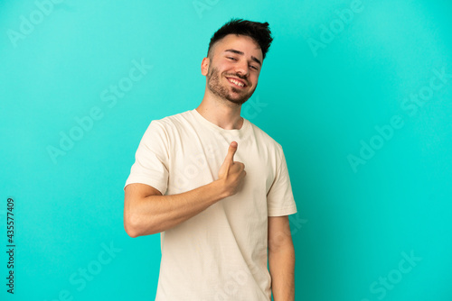Young caucasian man isolated on blue background giving a thumbs up gesture © luismolinero