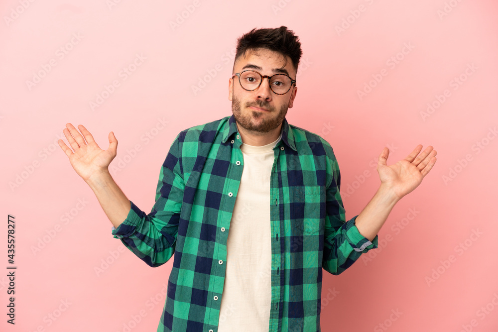 Young caucasian man isolated on pink background having doubts while raising hands Young caucasian man isolated on pink background having doubts while raising hands
