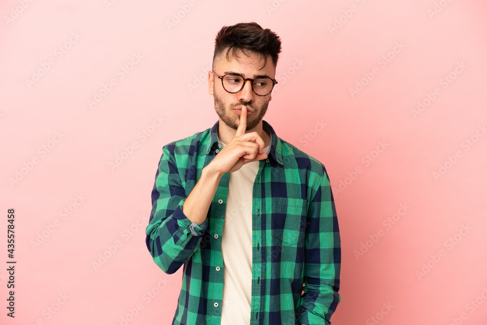 Young caucasian man isolated on pink background showing a sign of silence gesture putting finger in mouth Young caucasian man isolated on pink background showing a sign of silence gesture putting finger in mouth