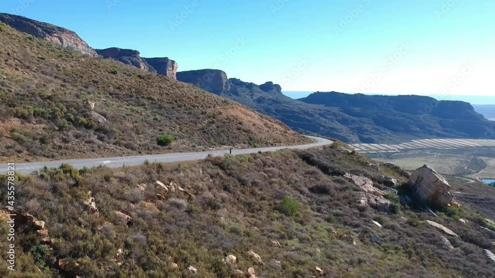 Tarmac road curving towards the camera in dry semi-desert landscape with mountains in the distance camera slowly moving up and back Aerial video Tarmac road curving towards the camera in dry semi-desert landscape with mountains in the distance camera slowly moving up and back Aerial video