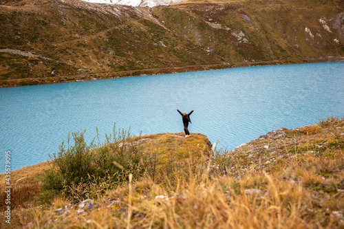 Mann mit erhobenen Händen und geber Mütze am Stausee  Lac de Moiry im Wallis in der Schweiz photo