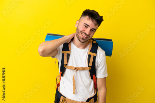 Young mountaineer caucasian man with a big backpack isolated on yellow background laughing