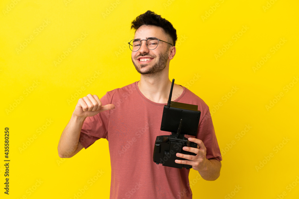 Man holding a drone remote control isolated on yellow background proud and self-satisfied Man holding a drone remote control isolated on yellow background proud and self-satisfied