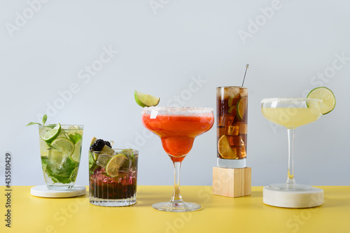 Photography Classic mojito, cuba libre, margarita cocktail with lime and lemon on modern blue and yellow background