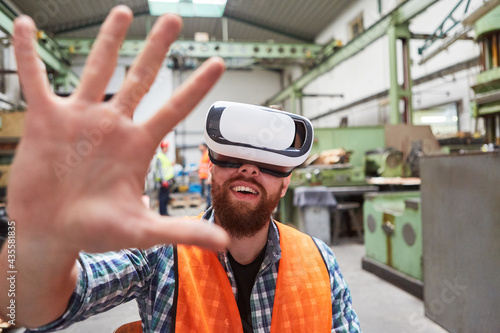 Arbeiter mit VR-Brille tastet in der Virtual Reality Fabrik