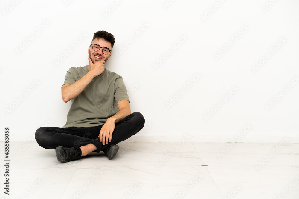 Young caucasian man sitting on the floor isolated on white background smiling Young caucasian man sitting on the floor isolated on white background smiling