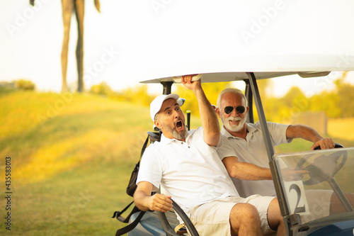 Two older friends are riding in a golf cart. Crazy ride on golf court.