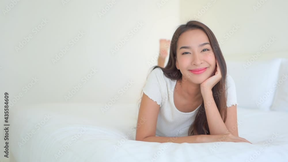 A young woman lying on a hotel suite bed smiles. Title space A young woman lying on a hotel suite bed smiles. Title space