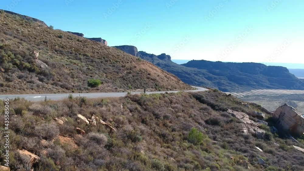 Tarmac road curving towards the camera in dry semi-desert landscape with mountains in the distance camera slowly moving back Aerial video. Tarmac road curving towards the camera in dry semi-desert landscape with mountains in the distance camera slowly moving back Aerial video.