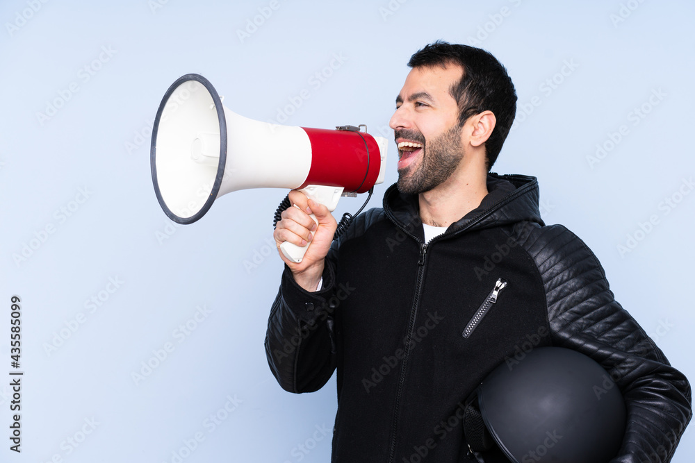 Man with a motorcycle helmet over isolated background shouting through a megaphone Man with a motorcycle helmet over isolated background shouting through a megaphone