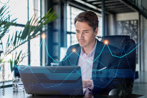 Fotografia Handsome businessman in suit at workplace working with laptop to optimize trading strategy at corporate finance fund