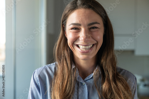 Cinematic shot of attractive happy young woman is smiling in camera in kitchen at home. Concept of life, family, health, happiness, femininity, women's day.