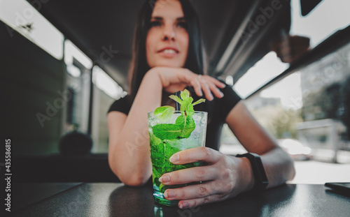 young teenager girl holding glass with a lemonade cocktail and drink in cafe