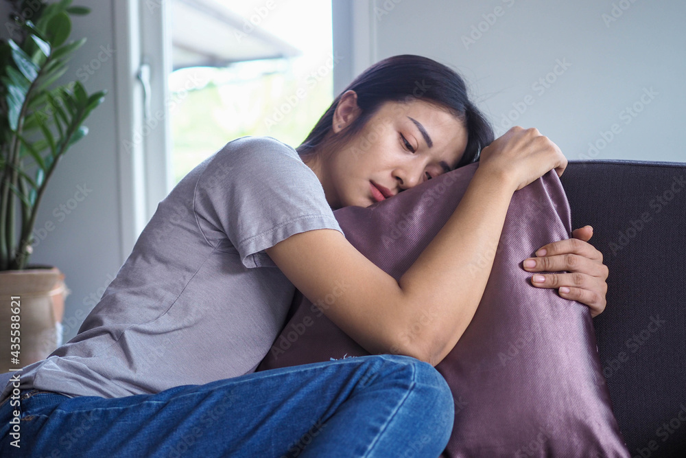 Obraz premium The girl hugged the pillow on the sofa inside the house sad and absent-minded feel bad about the things that happened.
