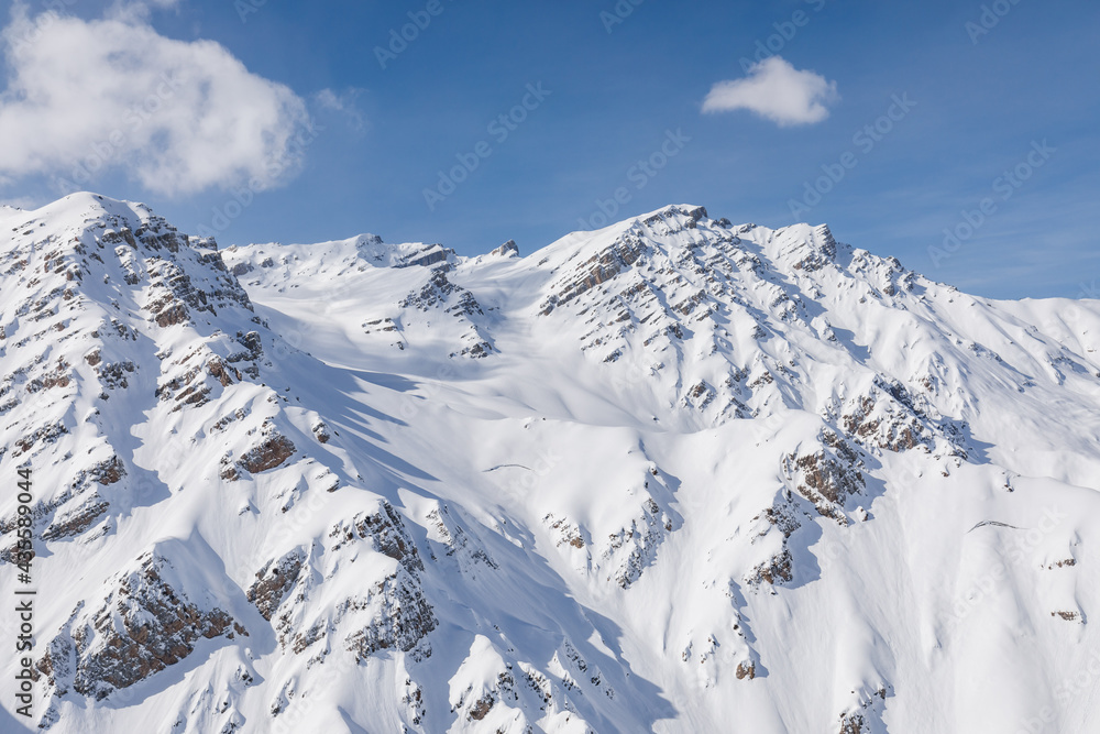 Obraz premium Winter snow mountains against blue sky and clouds from helicopter